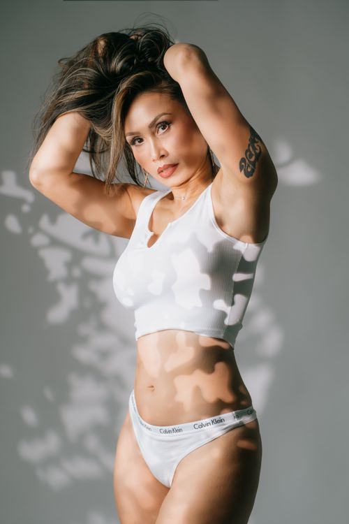 Free Dynamic portrait of an Asian woman modeling in white attire with visible tattoos, captured in fashion photography style. Stock Photo