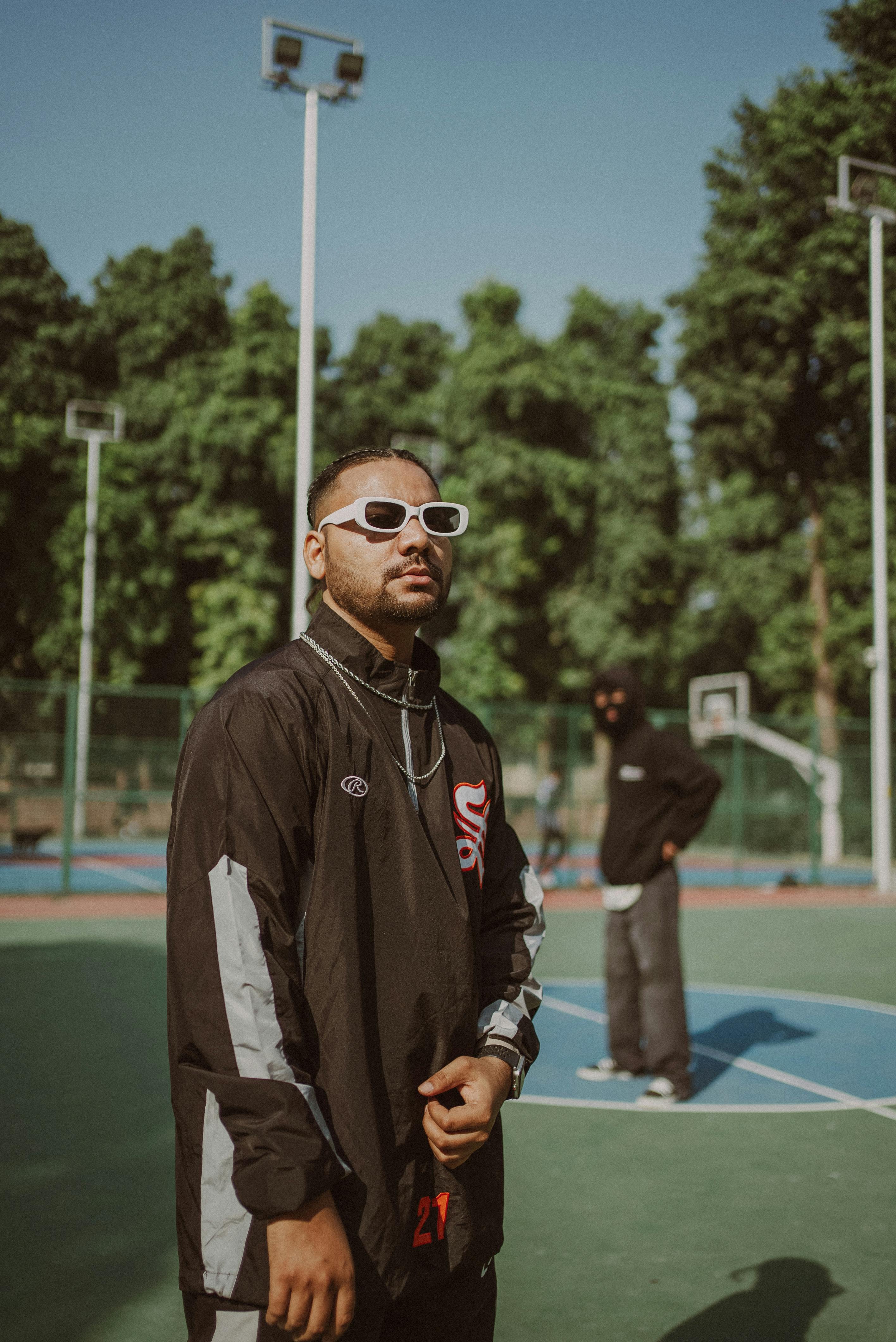 Stylish man in tracksuit and sunglasses on a basketball court in New Delhi.