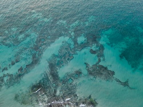 Free Beautiful aerial view of clear turquoise waters along a rugged coastline. Stock Photo