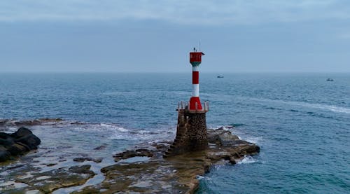 A Small Red and White Lighthouse on a Rocky Shore 