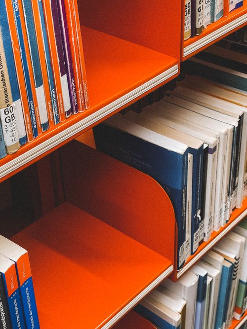 Free A high-angle view of a bright orange bookshelf filled with books in a German library. Stock Photo