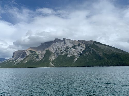 A mountain range with clouds and water in the background