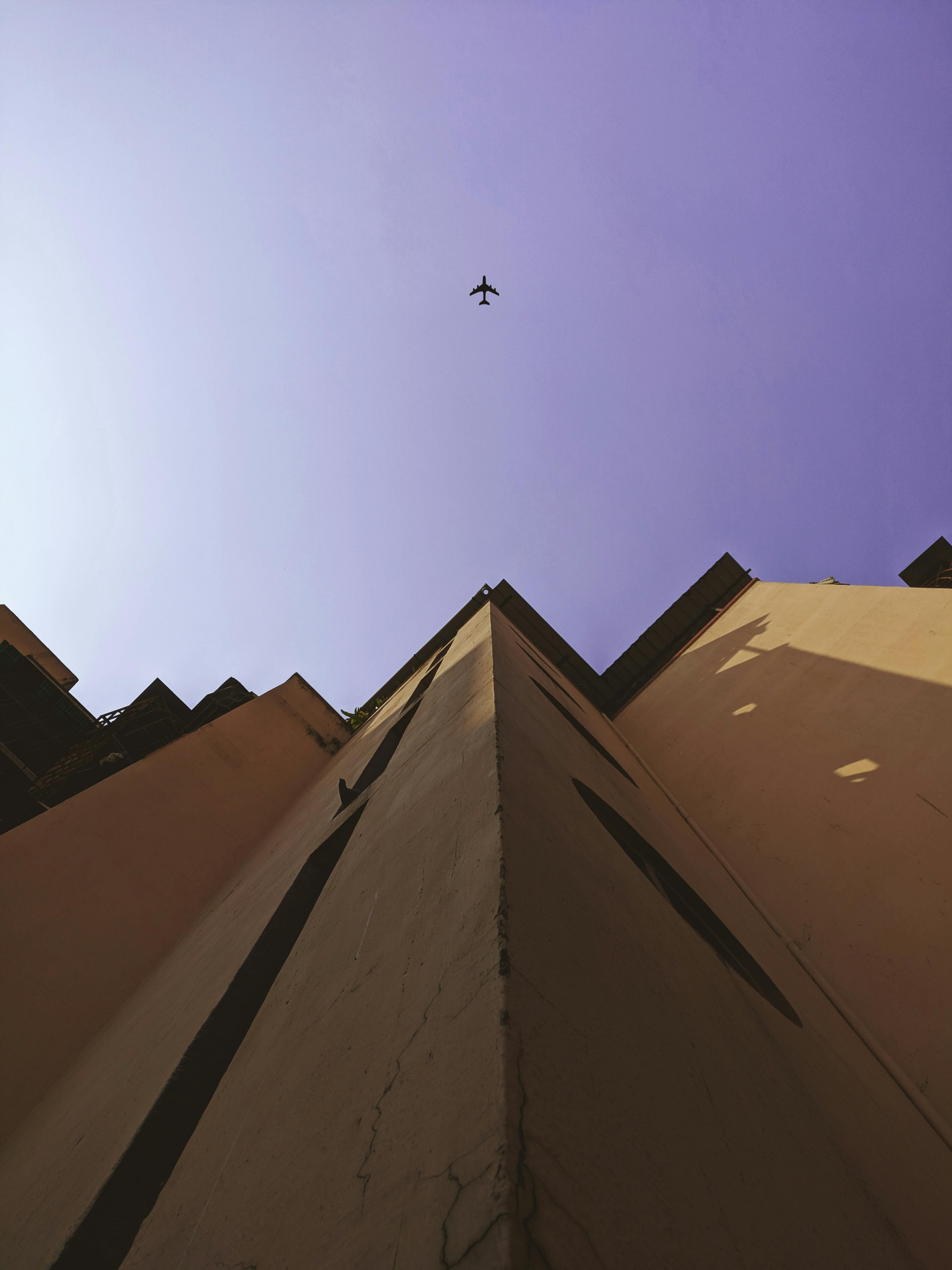 一架飞机飞过一座高大的城市建筑，在清澈的紫色天空中