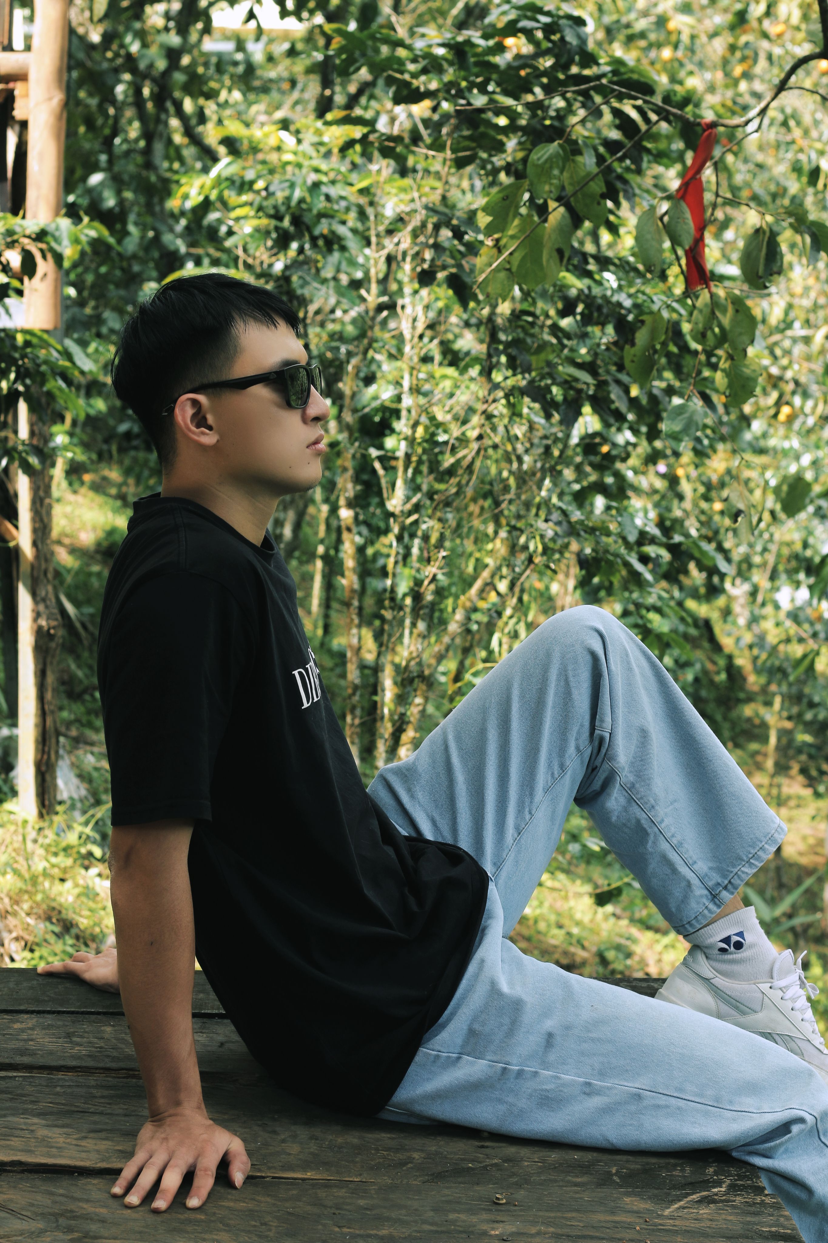 Young man in black t-shirt and jeans relaxing outdoors on a summer day.