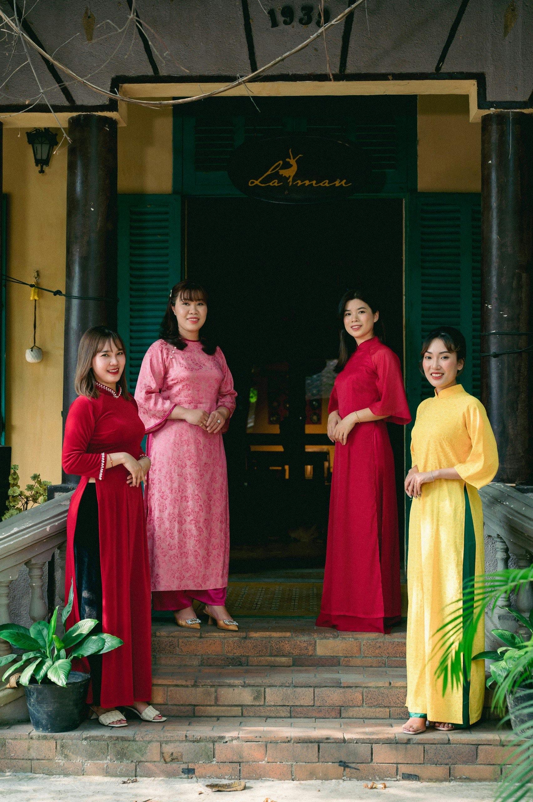 Four women in vibrant traditional dresses standing on stairs outside a classic building.