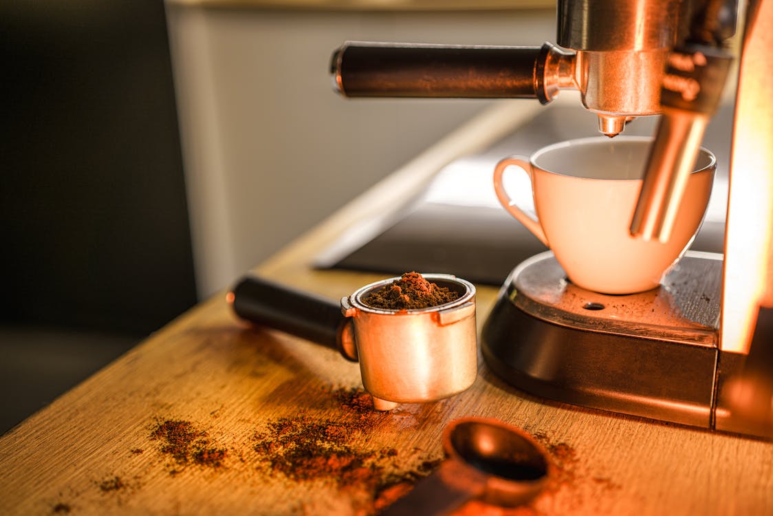 Close-up of Coffee in the Portafilter and a Cup Standing on a Coffee Machine 