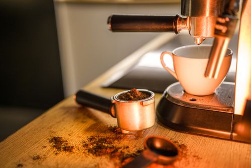 Free A detailed view of an espresso machine brewing coffee with a cup and portafilter on a wooden countertop. Stock Photo
