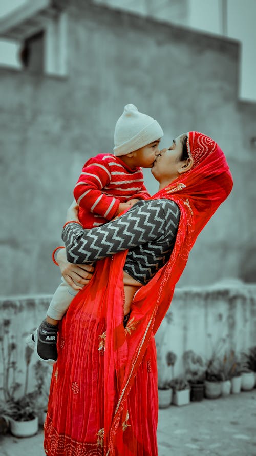Mother in Traditional Clothing Kissing Son