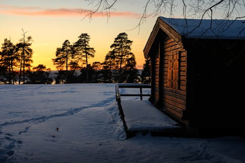 A cabin in the snow at sunset