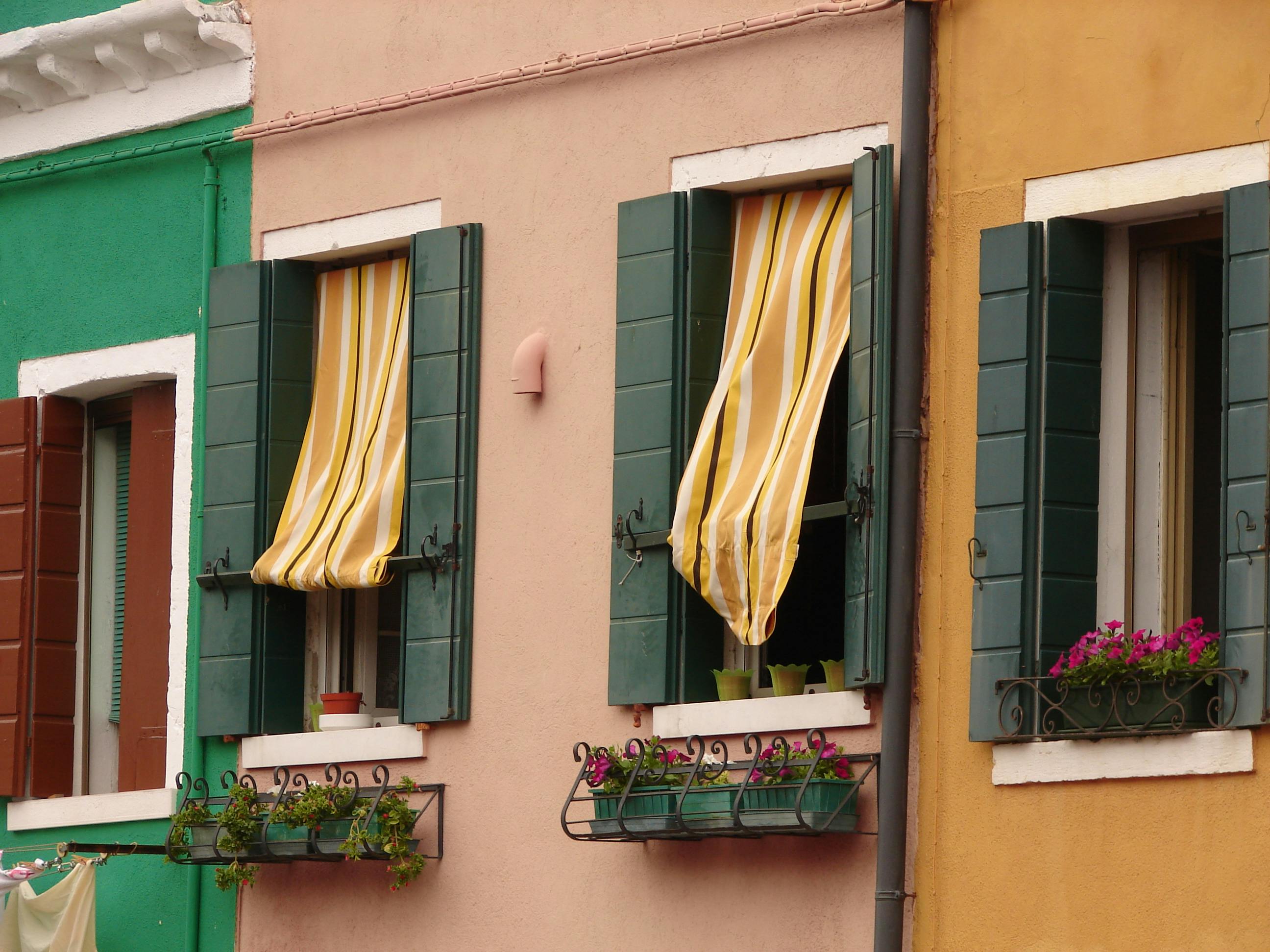 Vibrant urban facade with colorful walls and striped curtains over open windows.