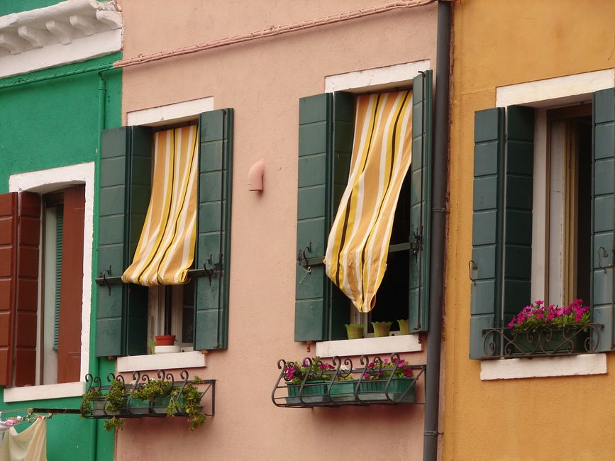 Vibrant urban facade with colorful walls and striped curtains over open windows.