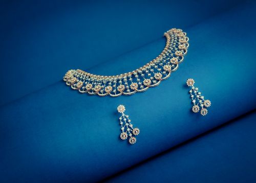 Free Elegant gold necklace and earrings on a vibrant blue backdrop. Stock Photo