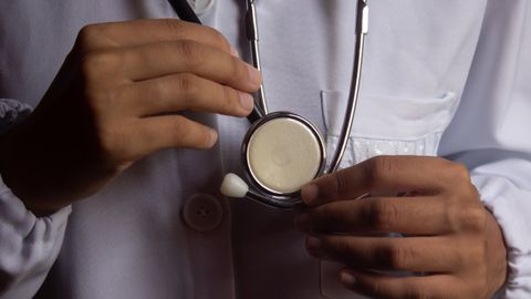 A close-up image showing a doctor holding a stethoscope, symbolizing healthcare and medical practice.