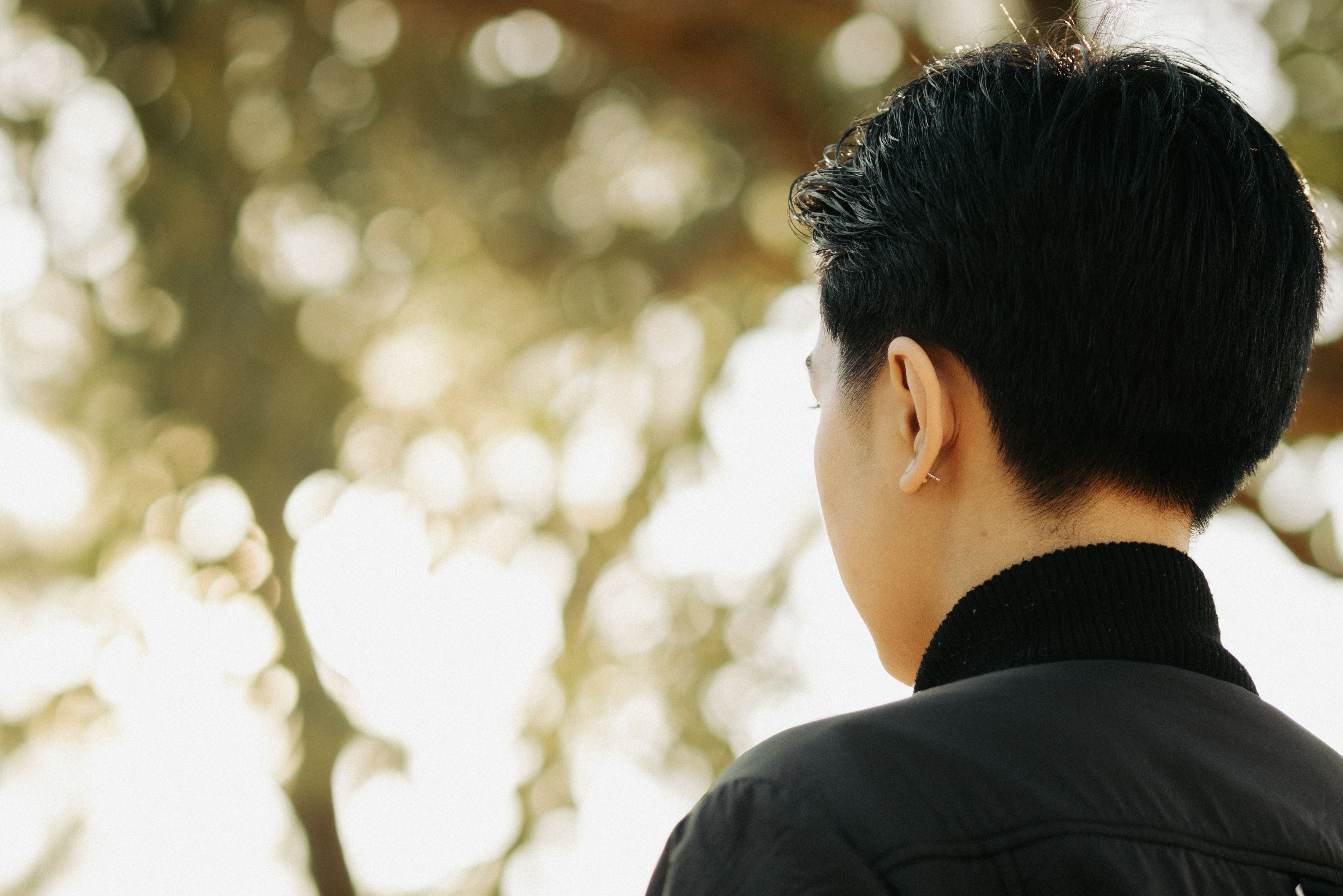 Free A peaceful back view of a person outdoors with sunlight through trees. Stock Photo