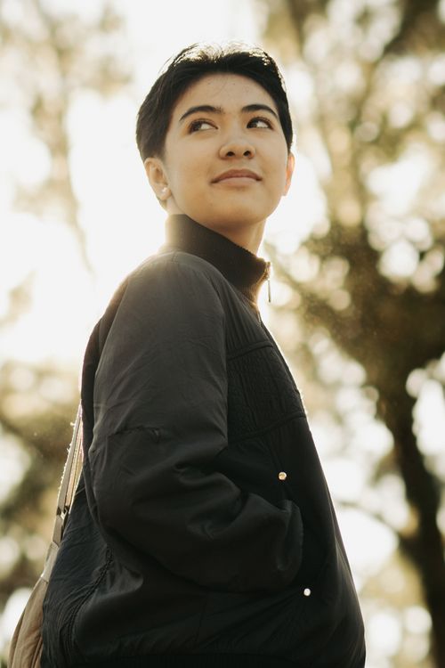 Free A stylish portrait of a woman with short hair, standing outdoors in a black jacket, smiling and confident. Stock Photo