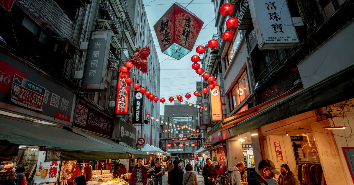 A bustling city street with illuminated lanterns and people at a night market.