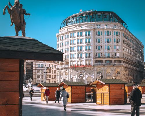 Free People walking near hotel and wooden booths in Skopje, showcasing urban architecture. Stock Photo