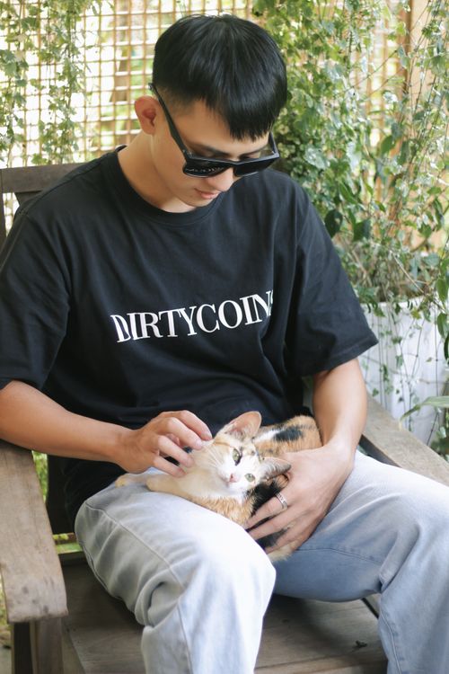 Free A man sits on a bench outdoors gently petting a calm cat on his lap, enjoying the serene environment. Stock Photo
