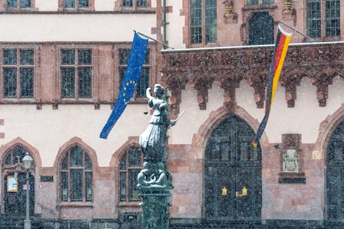 Justice Sculpture near Building with Flags of Germany and European Union