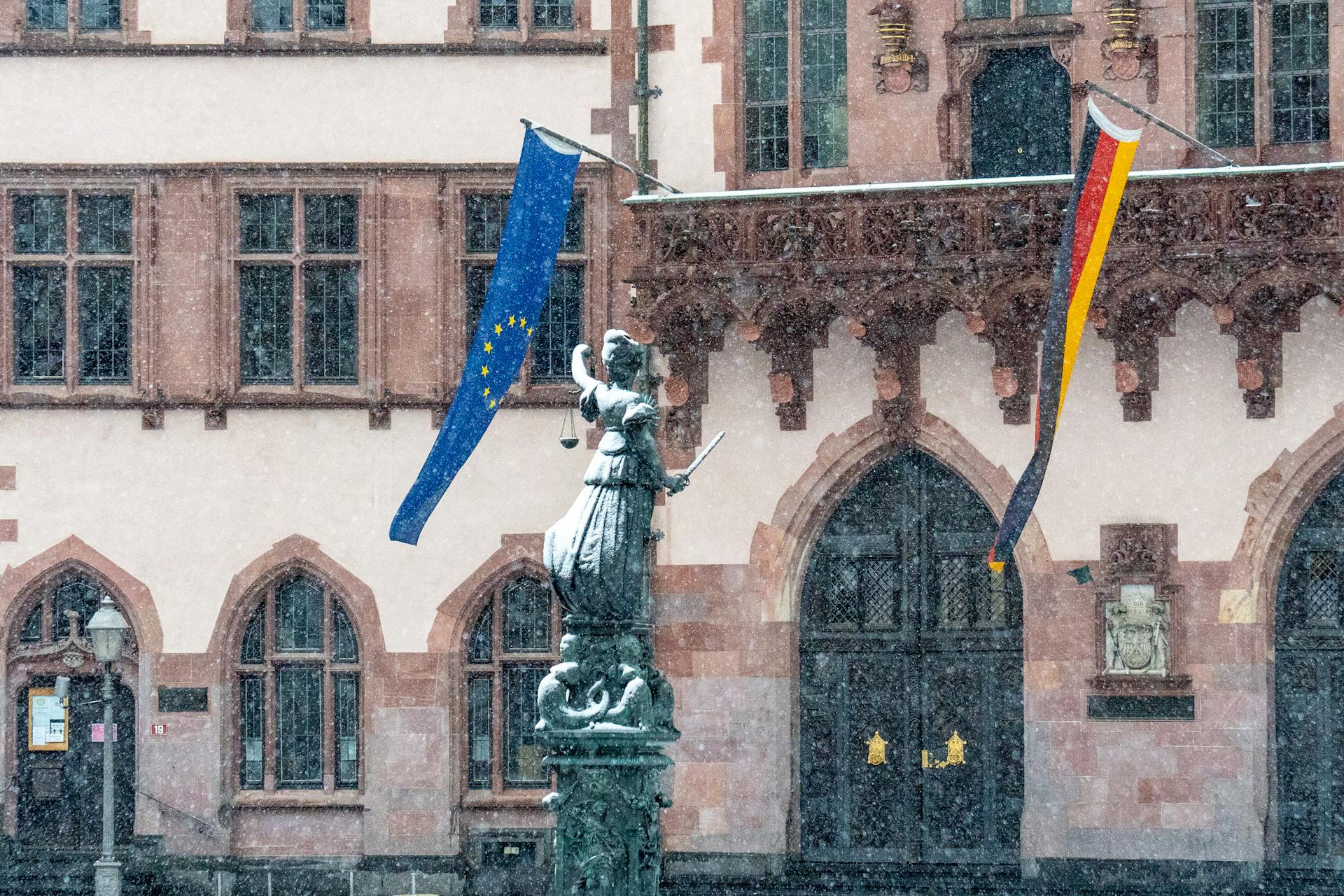 Justice Sculpture near Building with Flags of Germany and European Union