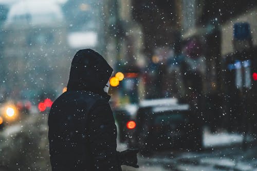 Snowfall over Man in Jacket on Street in Winter