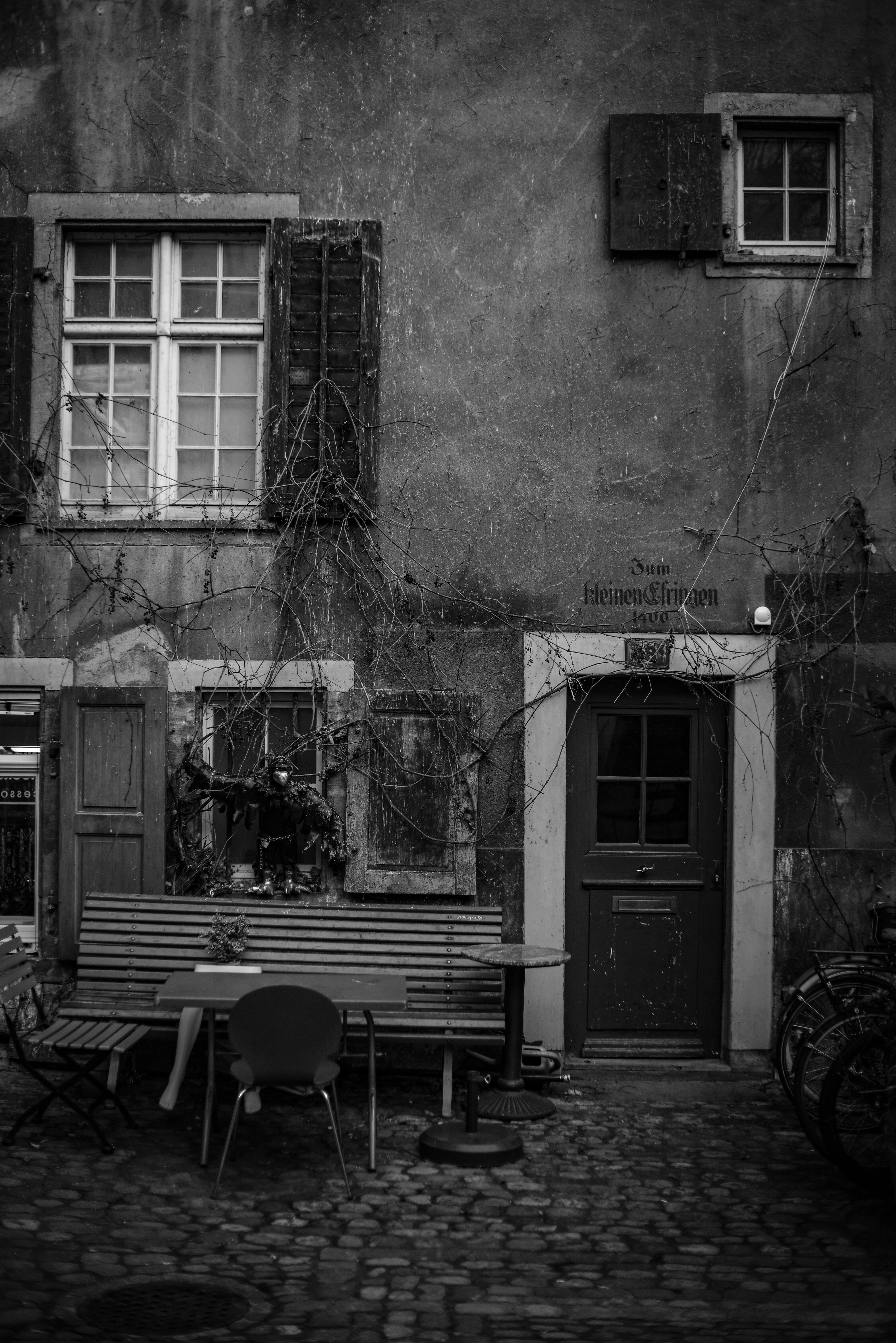 A rustic urban courtyard with benches and tables set against a vintage wall.