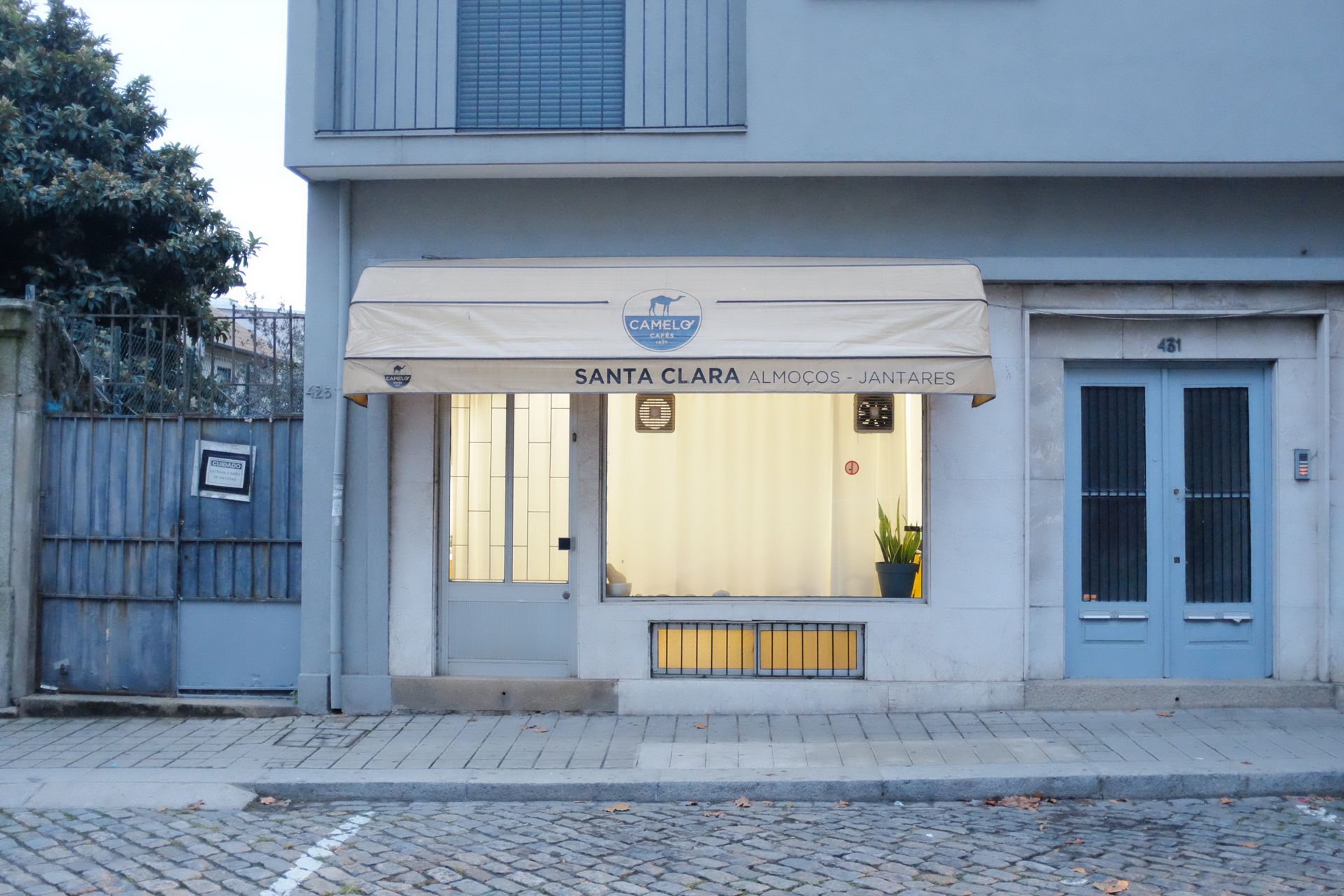 Cafe Santa Clara facade with cream awning and blue doors on a quiet street in Porto.