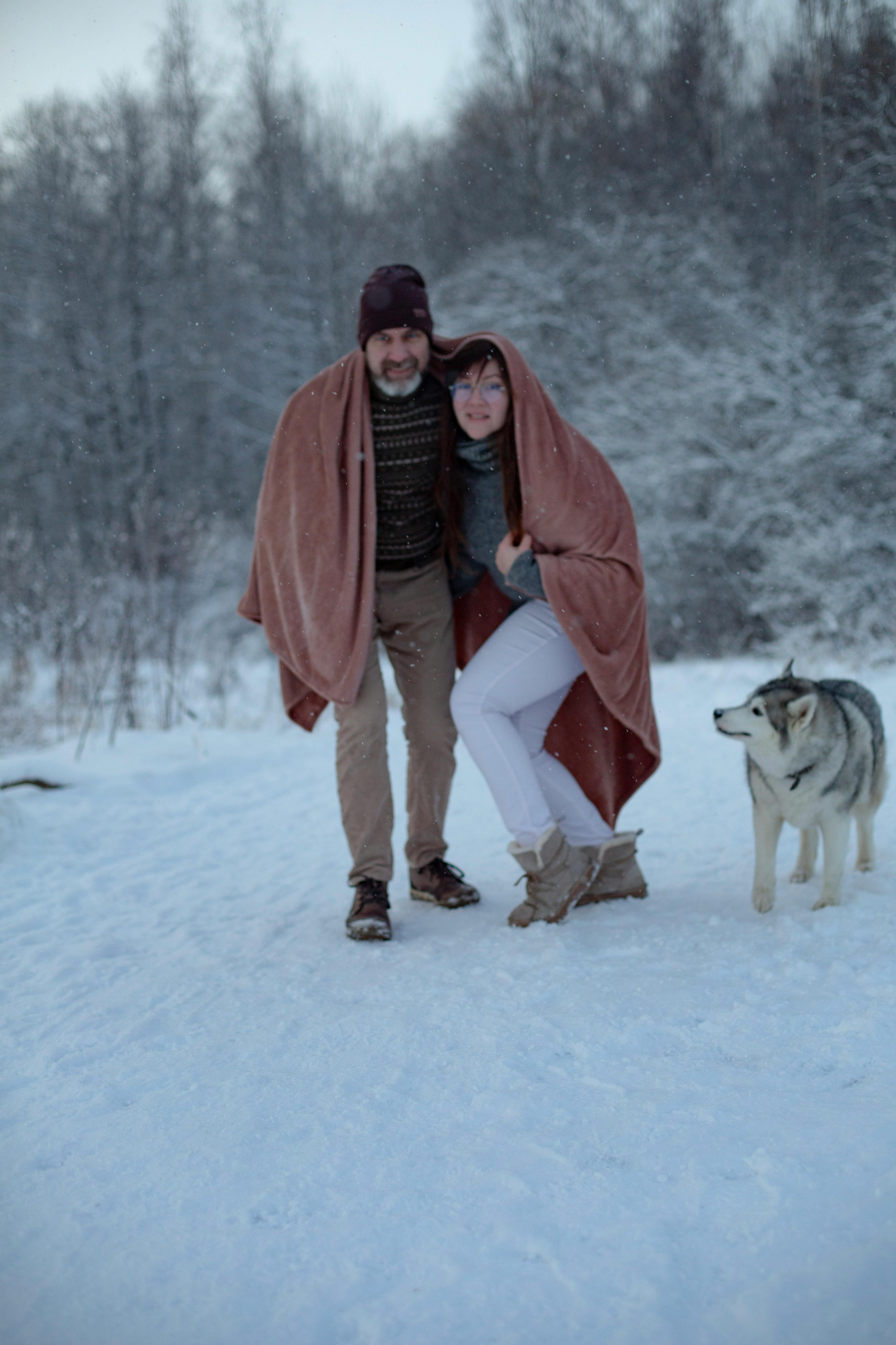 a man and woman wrapped in blankets on the snow