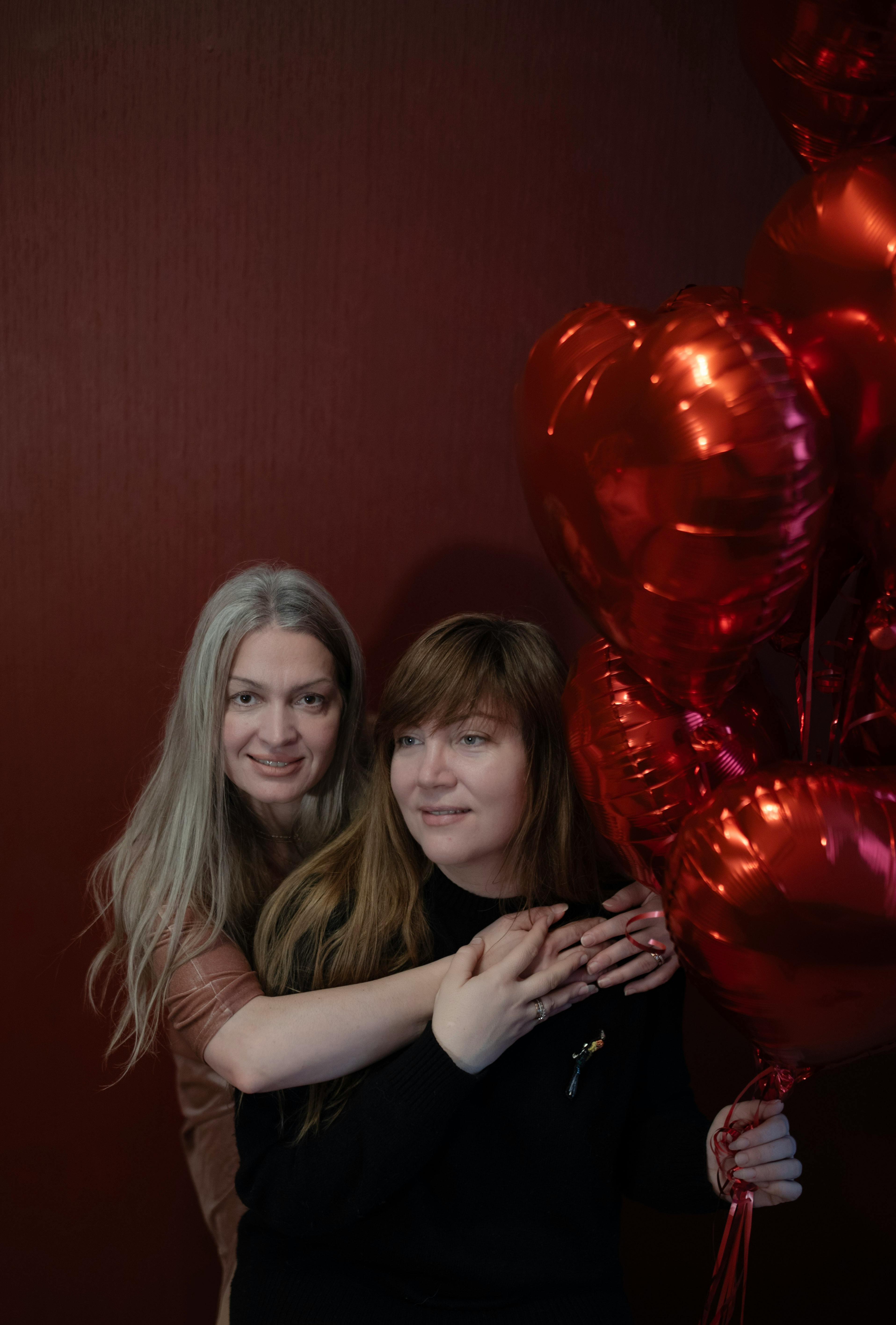 Smiling couple embracing with heart-shaped balloons and a festive mood.