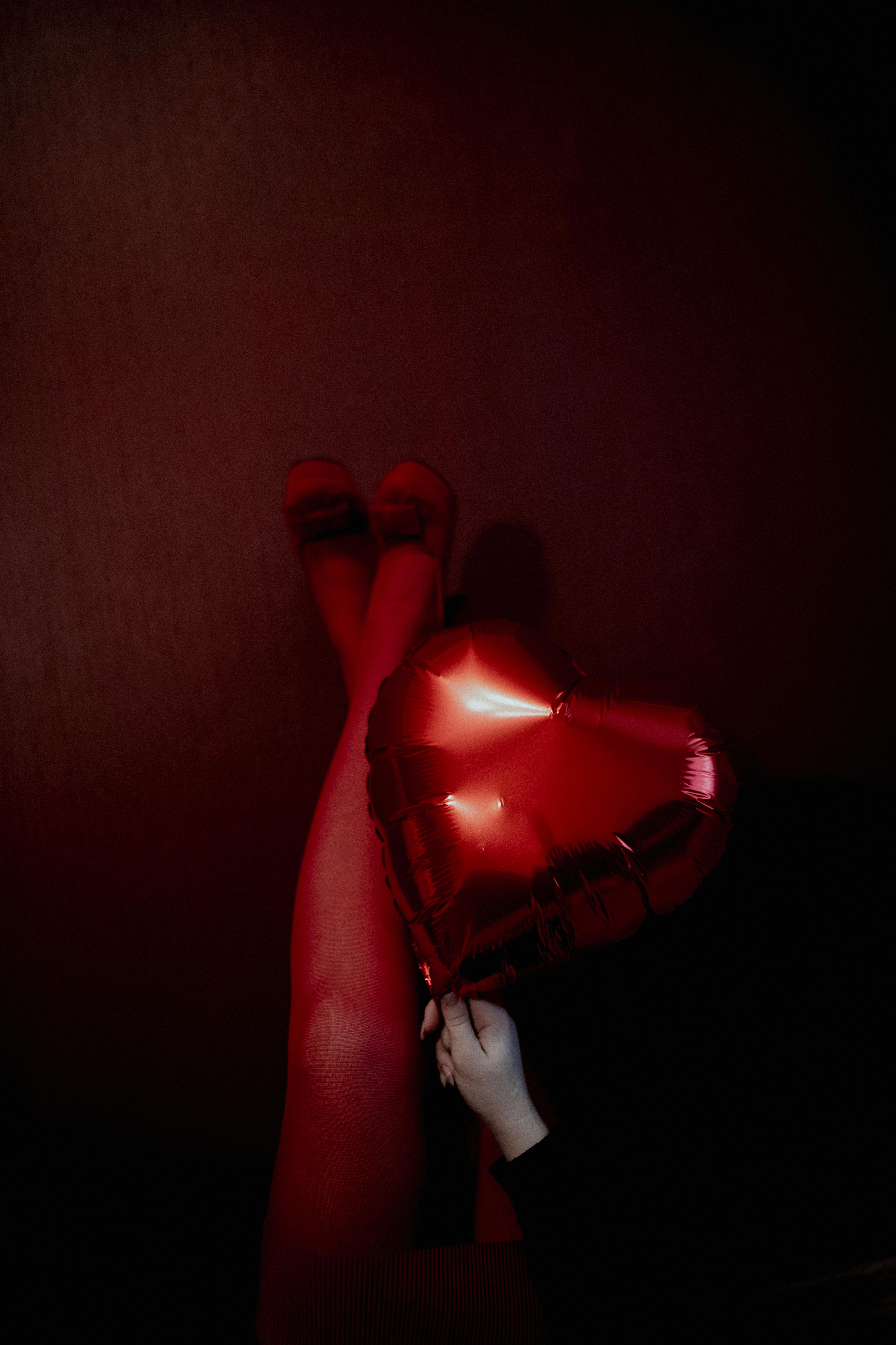 a woman in red tights holding a red heart balloon