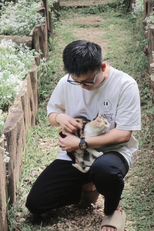 Man Crouching and Patting Cat