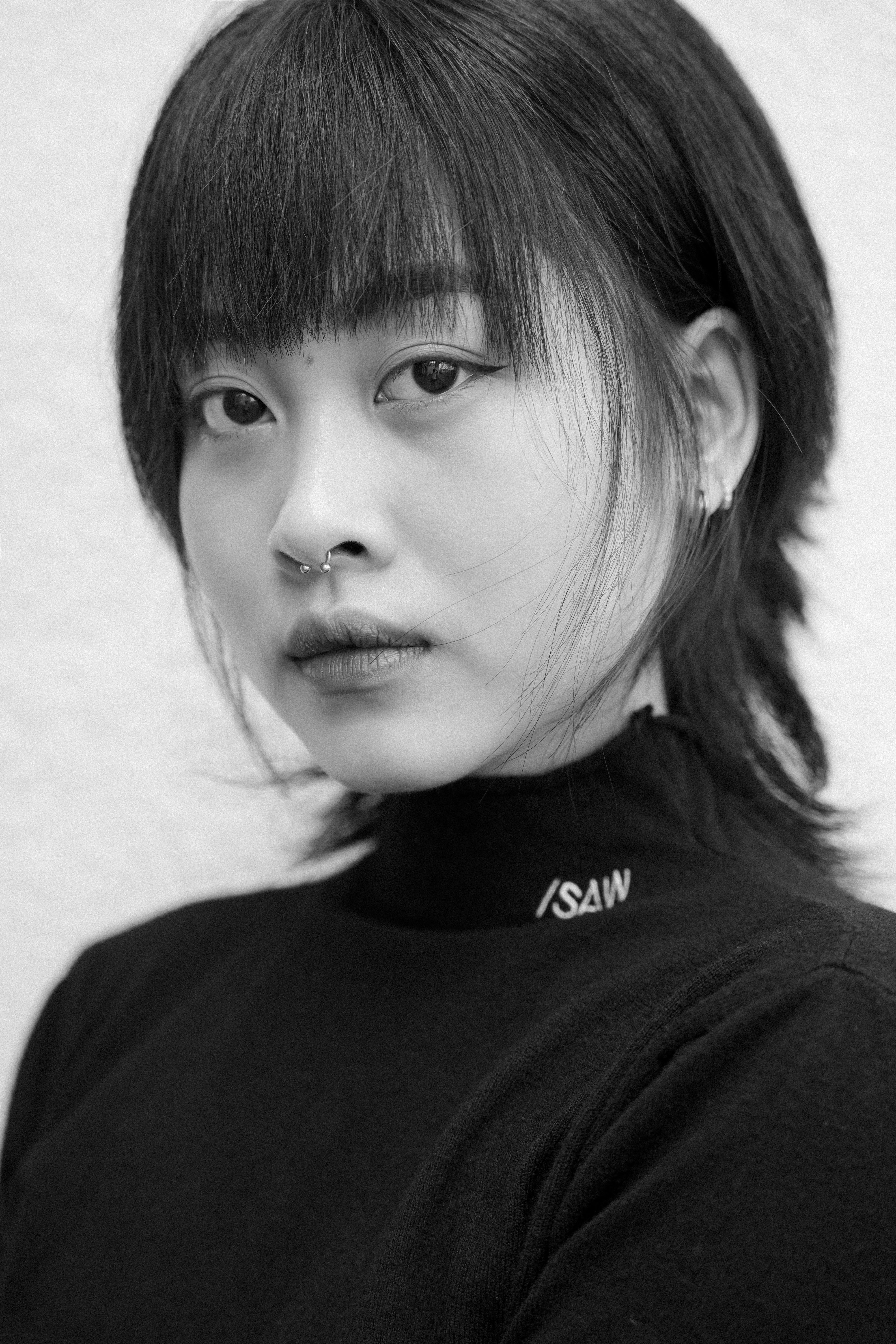Black and white portrait of a fashionable young woman wearing a turtleneck sweater.