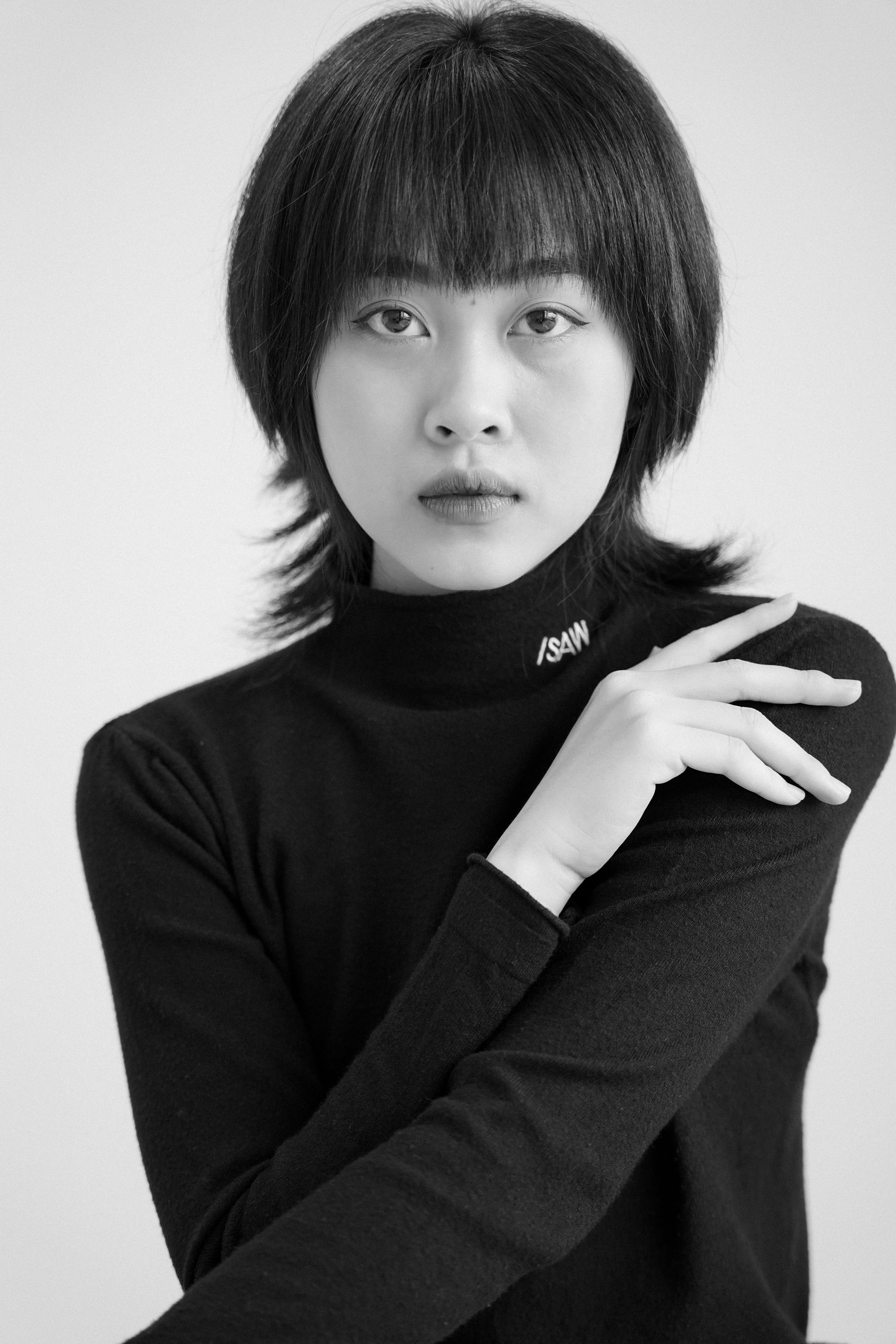 Striking black and white studio portrait of a woman in a turtleneck.