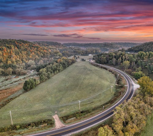 Aerial View of a Road, Fields and Trees under a Dramatic Sunset Sky 