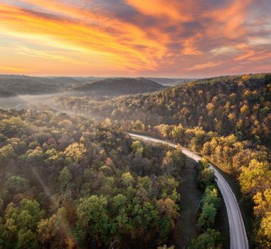 A stunning aerial view of a winding road through a forest at sunrise, West Albany, MN.
