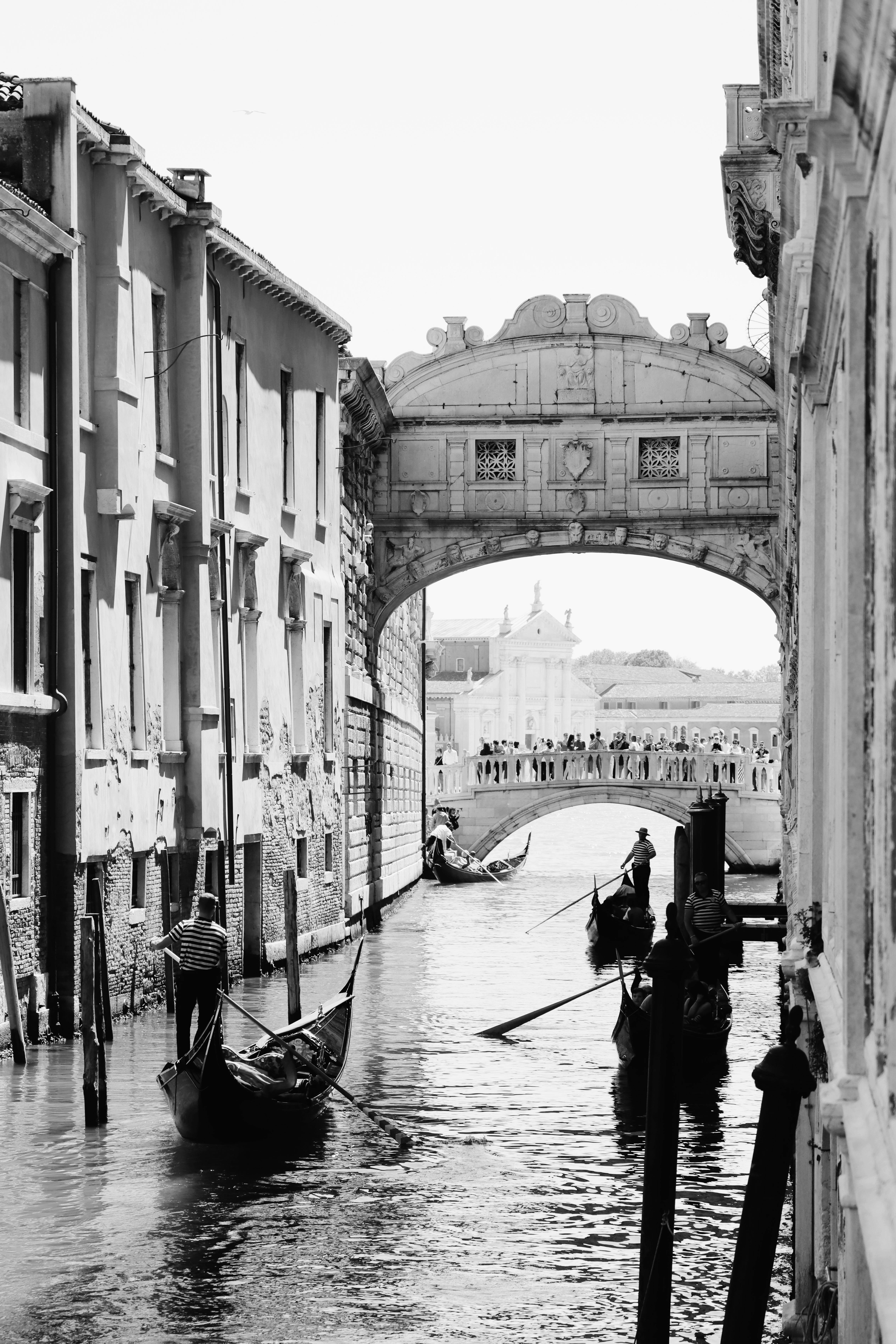 Stunning black and white image of gondolas navigating a historic canal in Venice, Italy.