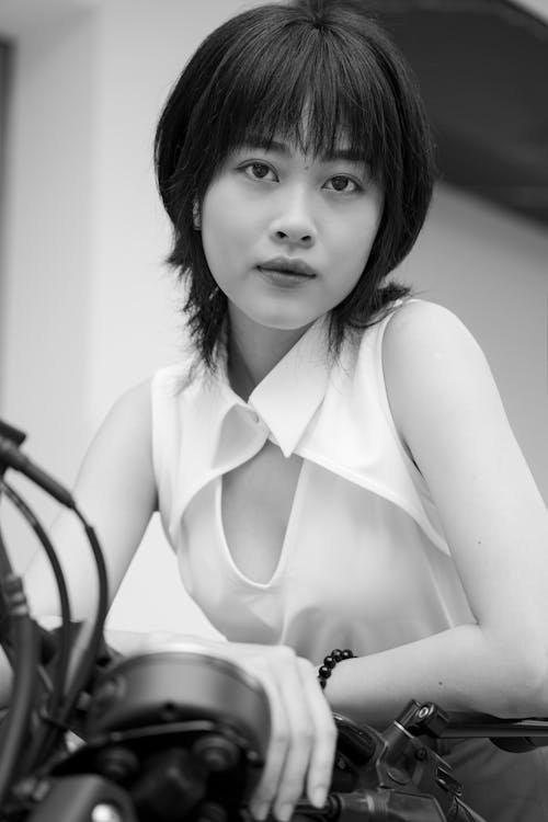 A woman sitting on a motorcycle in black and white