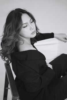 Elegant black and white portrait of a woman sitting with eyes closed in serenity.