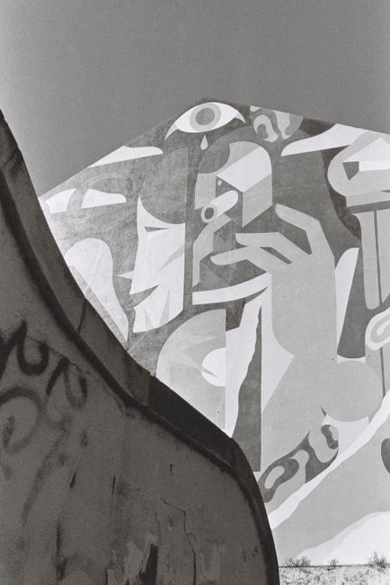 Urban graffiti mural in Lisbon, showcasing modern art against a clear sky.