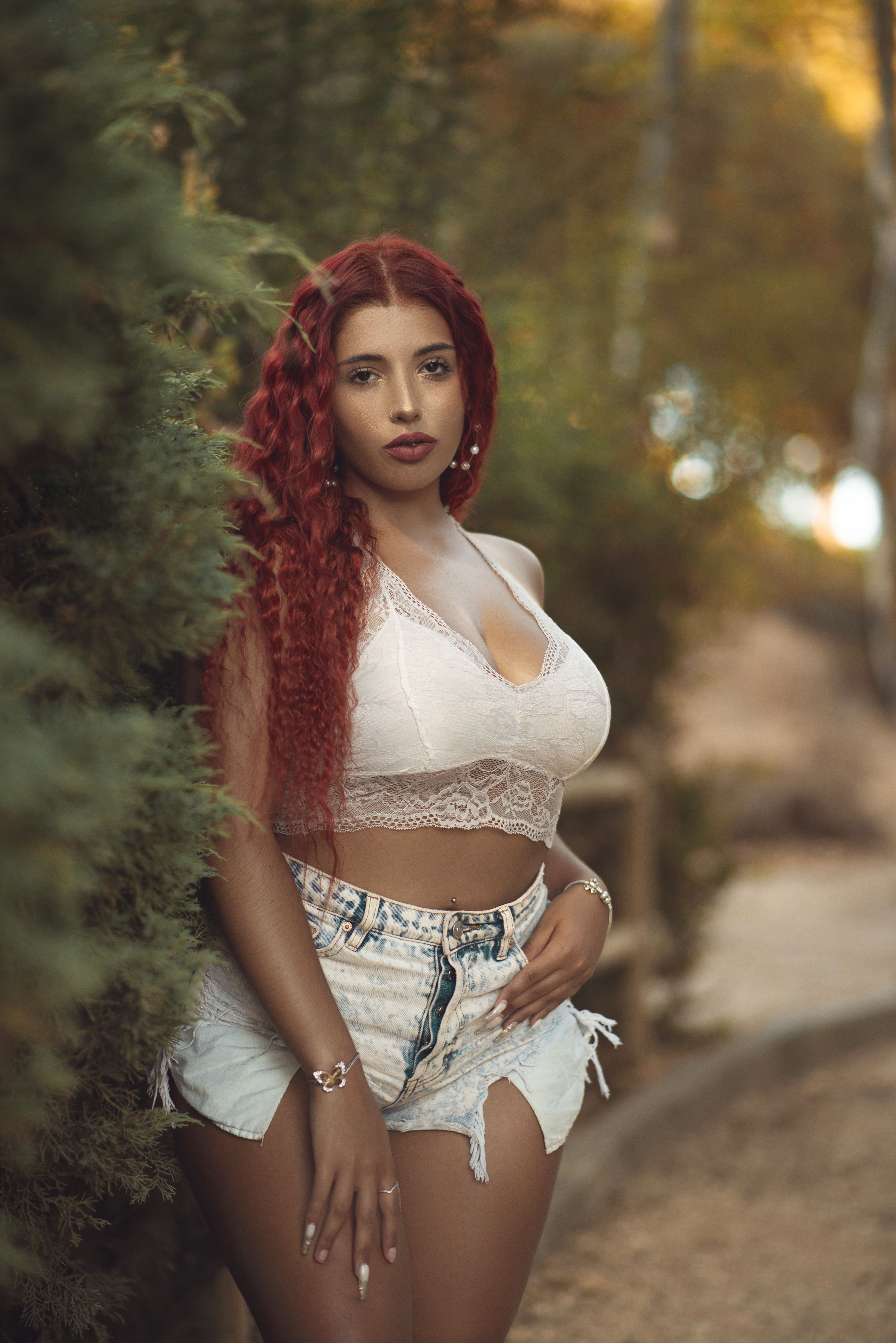 Fashion portrait of a woman with red hair in a natural outdoor setting.