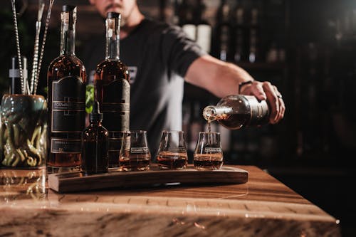 A man pouring a drink into a glass on a bar