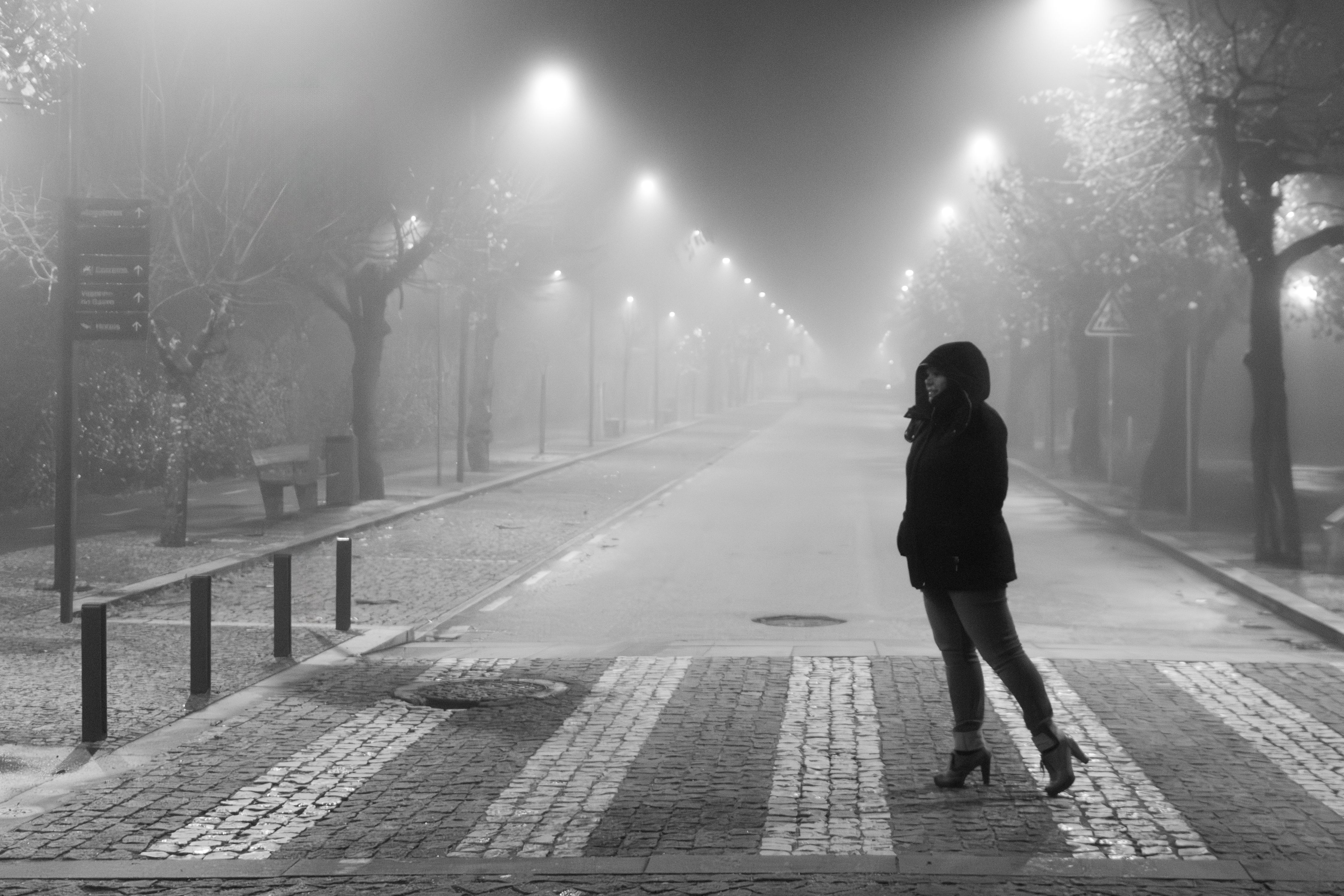 Woman crossing foggy street at night in Anadia, Portugal. Atmospheric and mysterious mood.