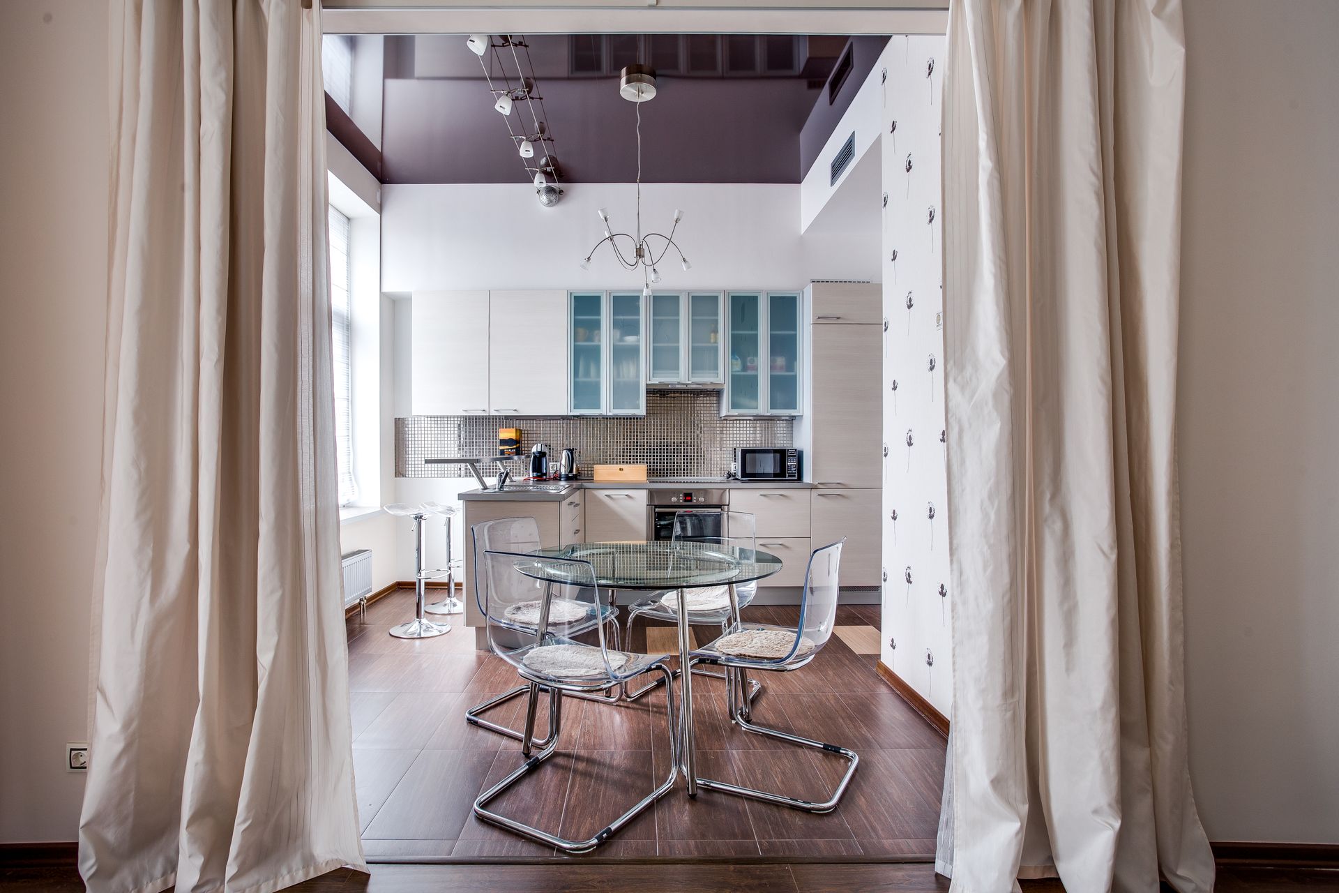 Sleek modern kitchen design featuring glass table, chairs, and contemporary appliances.