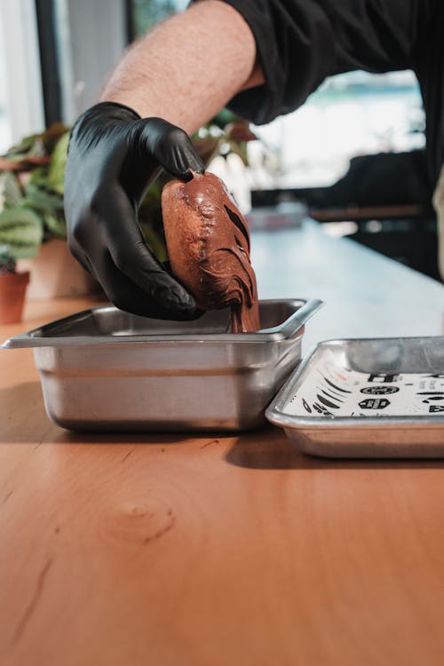 A person in gloves is making chocolate in a pan