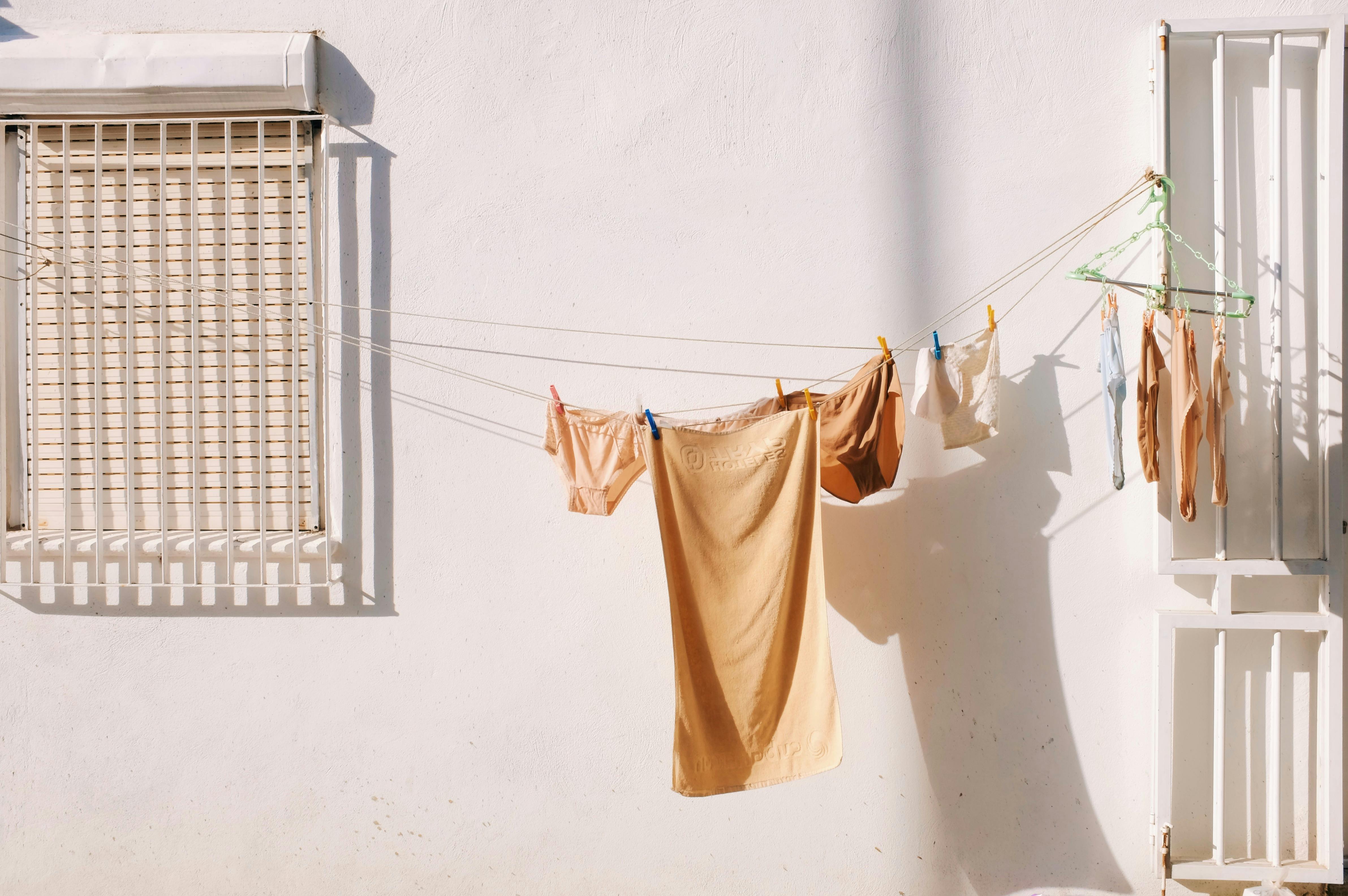 Clothes hanging on a clothesline outside a white wall in Porto, Portugal, capturing daily life in warm sunlight.