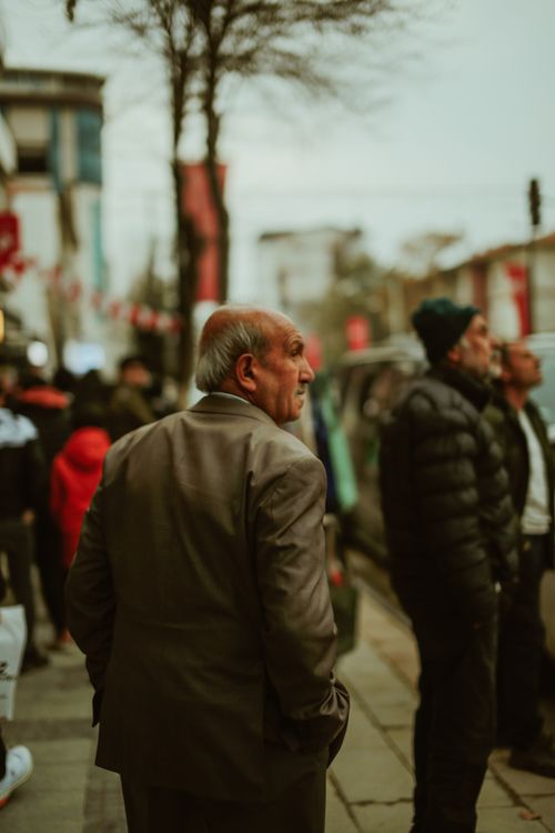 Free Elderly man with gray hair walks through a busy urban street filled with people. Stock Photo