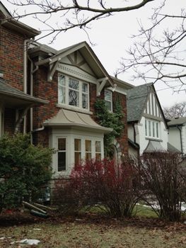 Cozy two-story brick house in Toronto with bushes and traditional architecture on a winter day.
