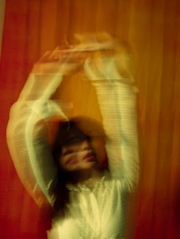 Abstract portrait with motion blur of a woman wearing a white shirt against a warm backdrop.