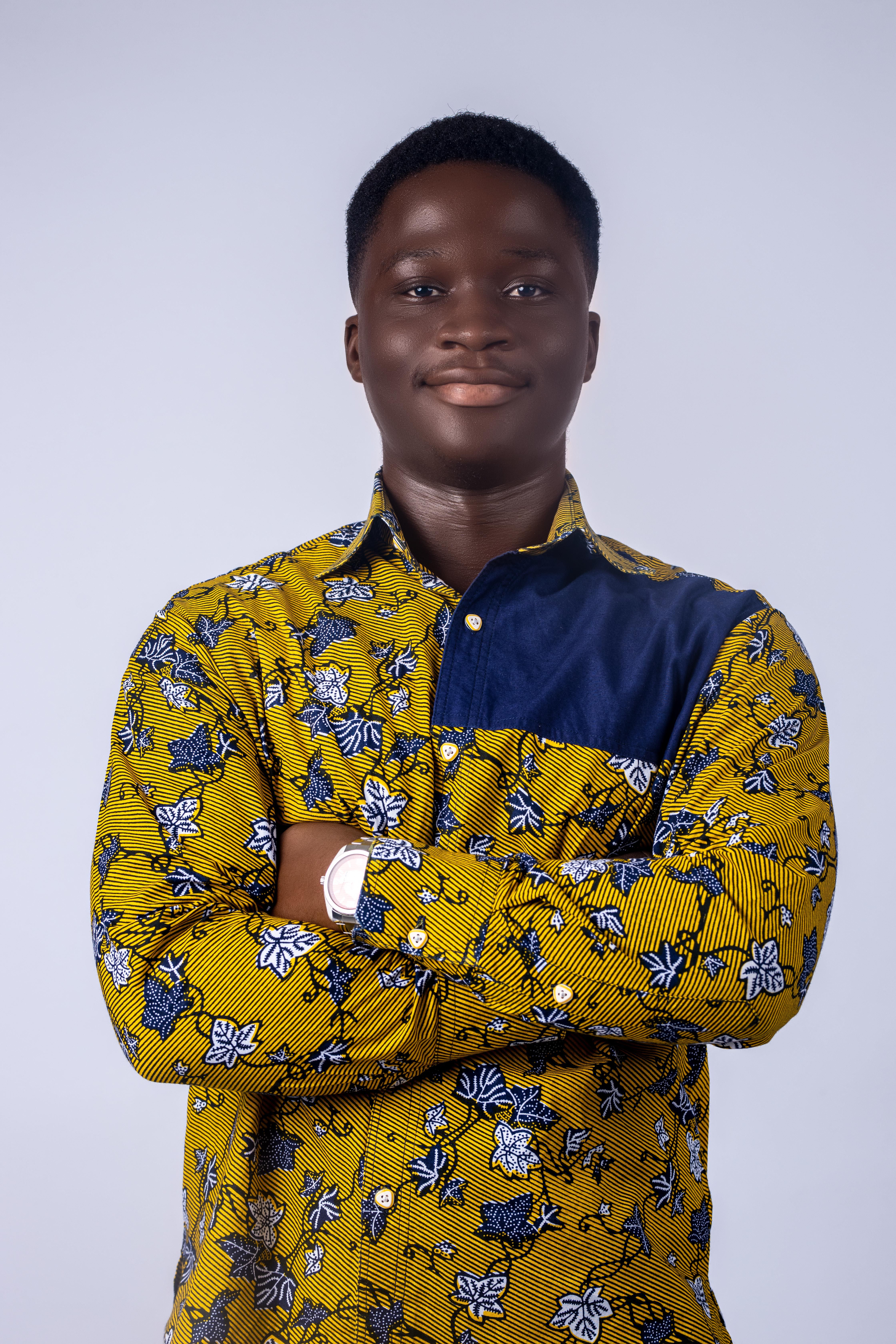 Portrait of a man in a yellow floral shirt with crossed arms, exuding confidence.