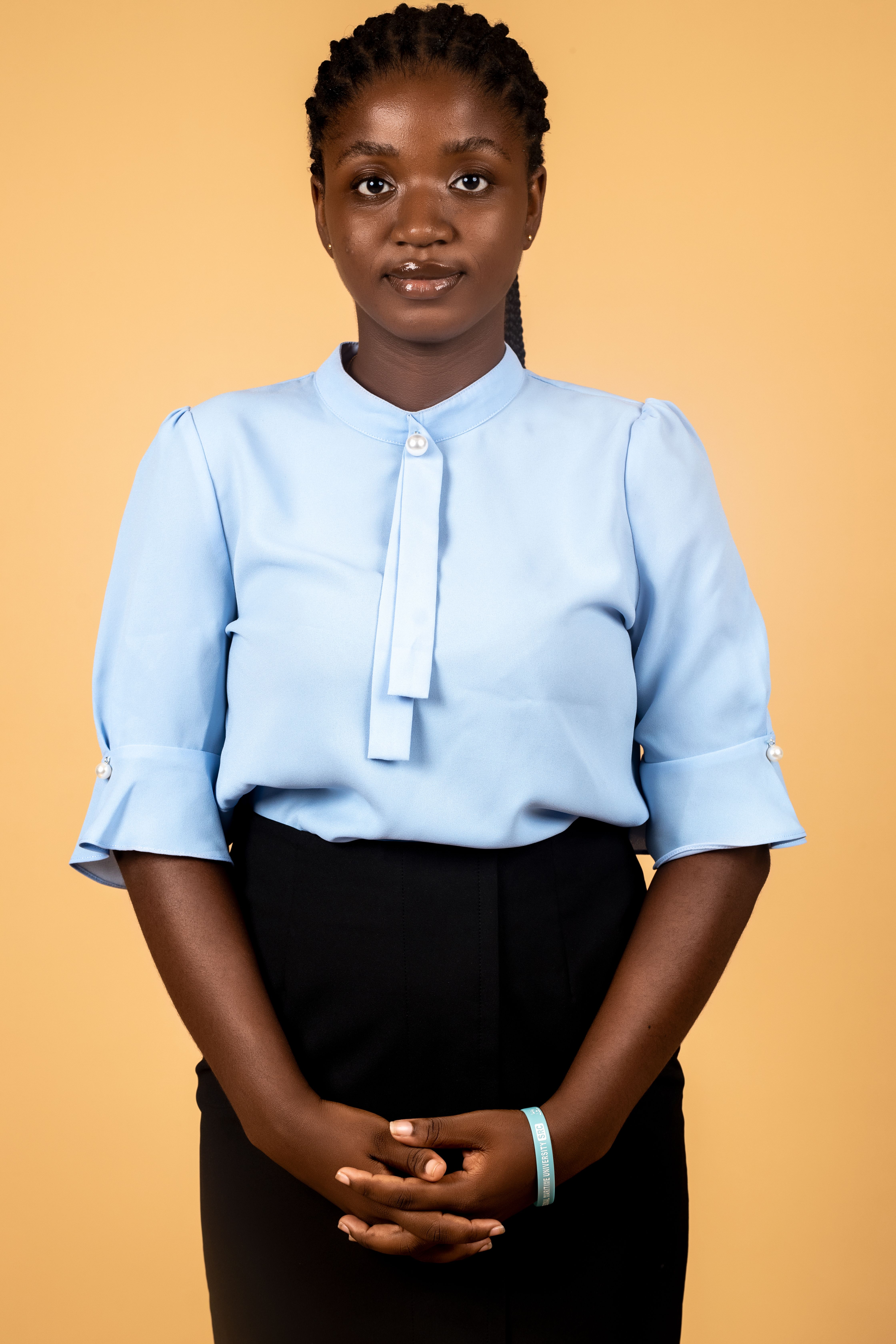 Elegant portrait of a woman in a blue blouse and black skirt against a brown background, studio setting.